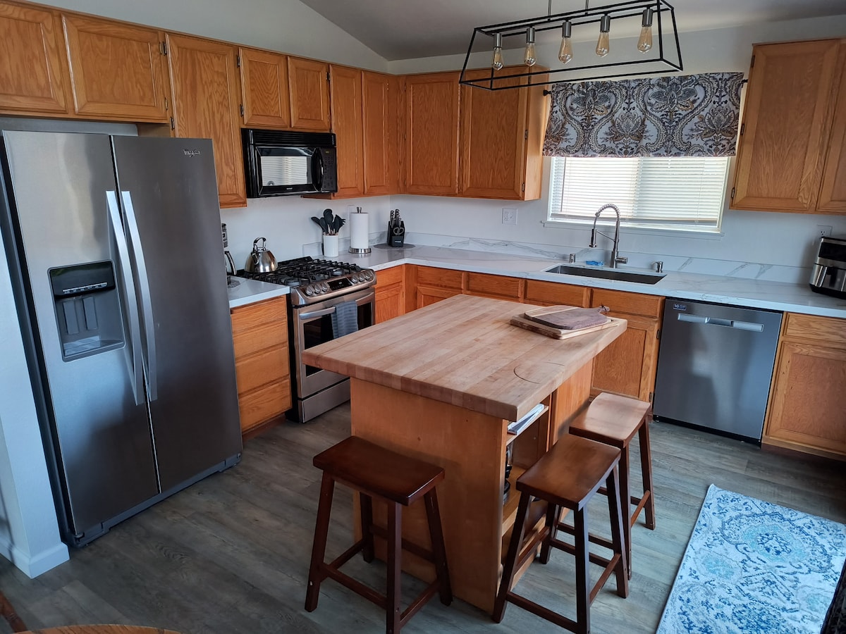 Kitchen with wood island, stools, gas range, and stainless appliances