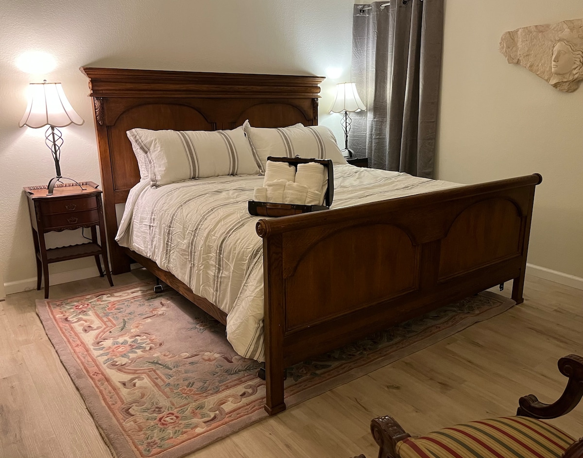 Master bedroom with a king sleigh bed, bedside lamps, and folded towels