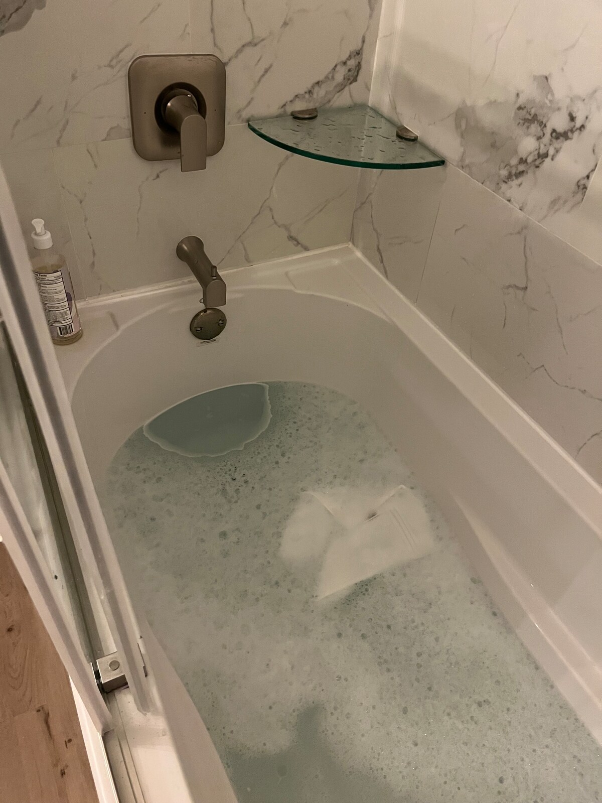 Main bath / marble soaker tub with marble tile and glass shelf